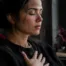 Woman sitting quietly by a window with her hand over her heart, practicing body awareness to process feelings without getting stuck.